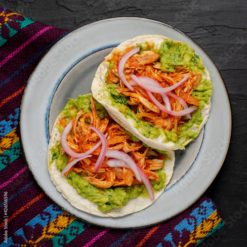 Chicken tinga tacos with guacamole and onion on dark background. Mexican food