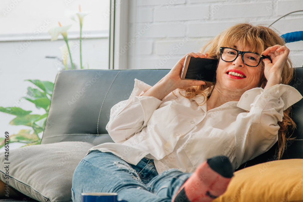 smiling woman with mobile phone on the sofa at home