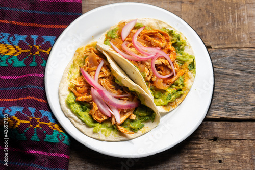 Chicken tinga tacos with guacamole and onion on wooden background. Mexican food