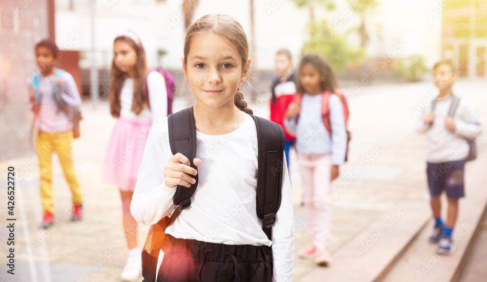 Obraz premium Portrait of smiling tween schoolgirl with backpack on her way to school on autumn day. Back to school concept.