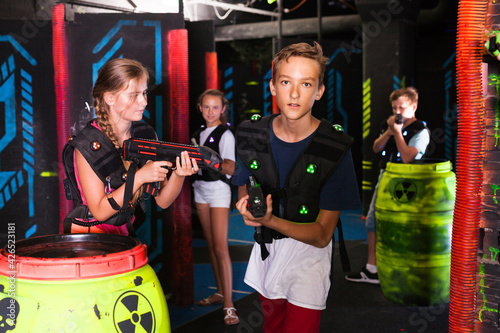Emotional teen boy with laser pistol playing laser tag with friends on dark labyrinth.. © JackF