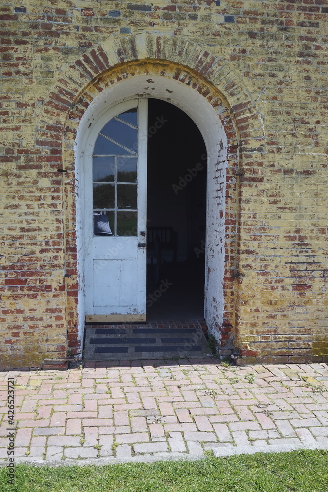 Fototapeta premium Colonial Arched Wooden Door on Brick Building in Daylight