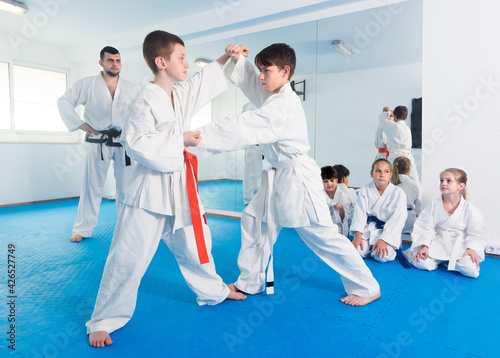 Happy boys training in pair to use karate technique during class