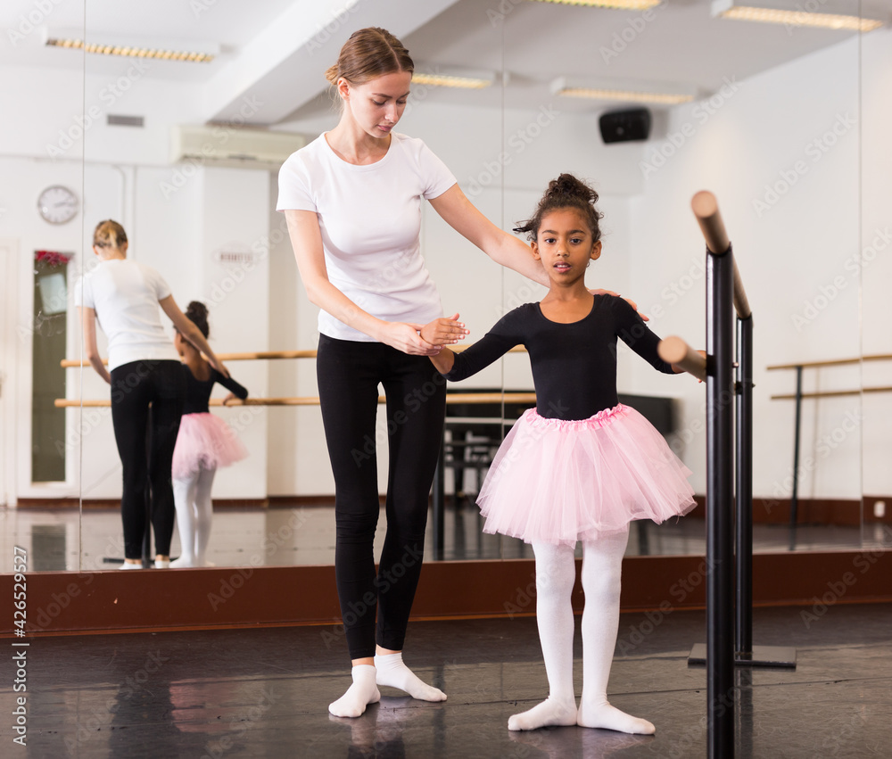 Young female choreographer and little Latin girl in classical dance school