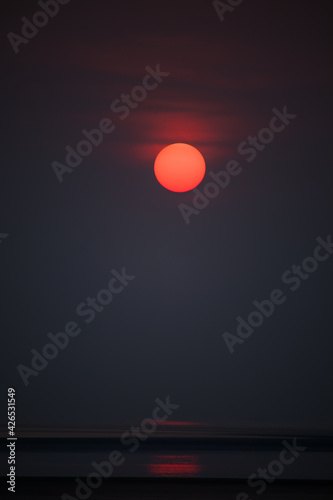 Canvas Print View of the red sun shining bright at dusk over the sea
