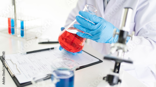 Young Asian scientist Working looking through a microscope doing research for analyzing a Experiments sample in a forensic laboratory.