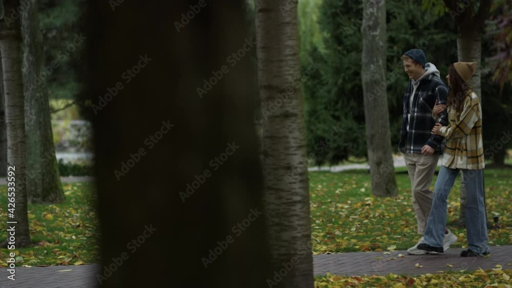 Smiling young lovers walking in beautiful autumn park.Girl and guy walking . Smiling young lovers walking in beautiful autumn park.Girl and guy walking .