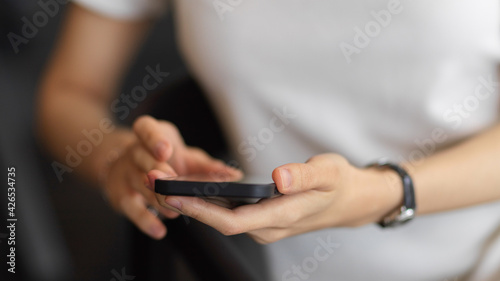 A woman using smartphone in her hands while sitting on the armchair