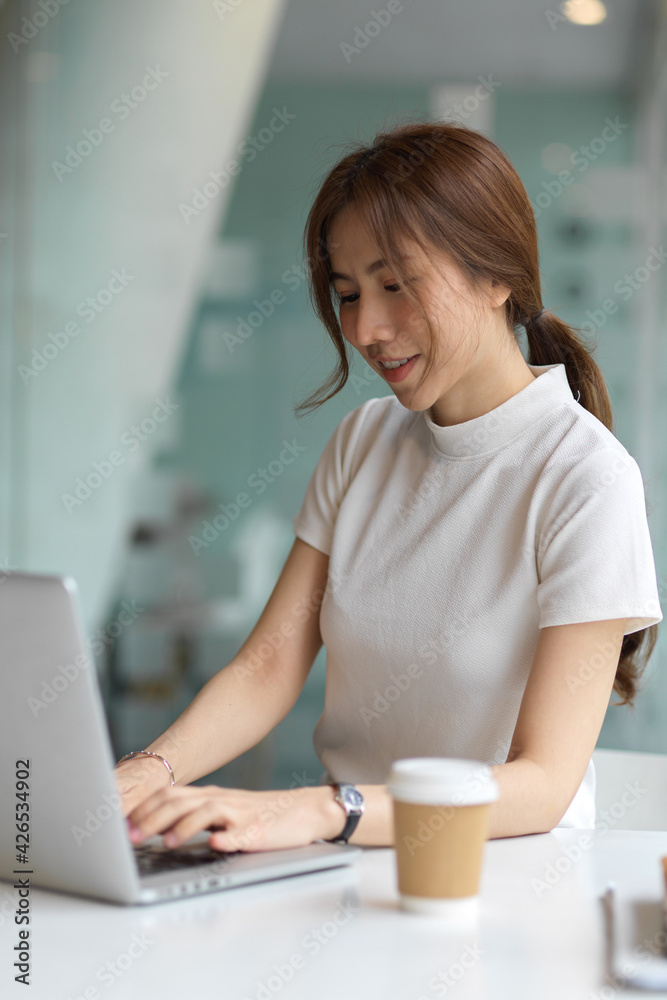Cropped shot of female using computer laptop on the table in co-working space Cropped shot of female using computer laptop on the table in co-working space