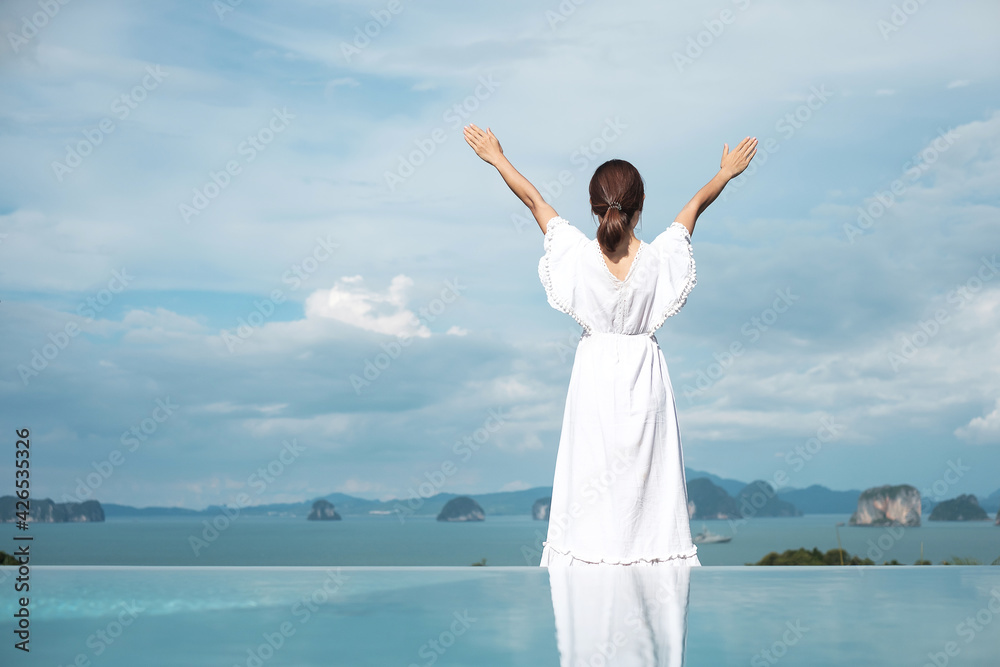 Happy traveler woman in white dress enjoy Beautiful view, alone Tourist with hat standing and relaxing over swimming pool. travel, summer and vacation concept Happy traveler woman in white dress enjoy Beautiful view, alone Tourist with hat standing and relaxing over swimming pool. travel, summer and vacation concept