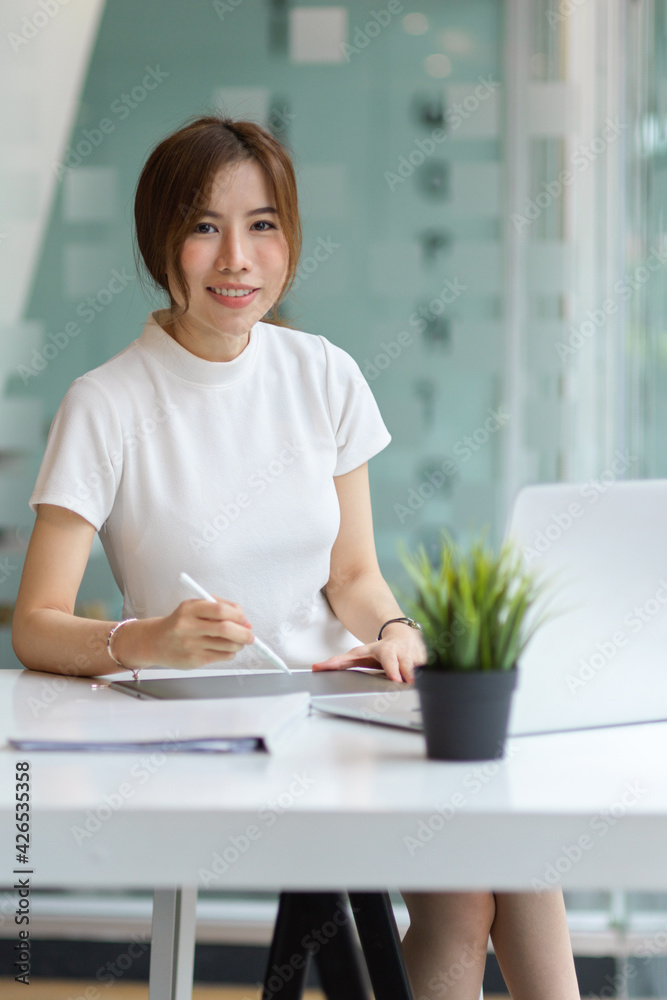 Portrait of female university student smiling to camera while doing assignment in library Portrait of female university student smiling to camera while doing assignment in library
