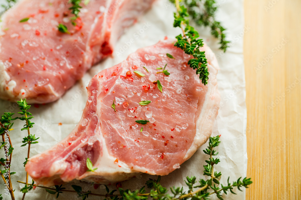 Raw pork meat with thyme and spices on the rustic background. Selective focus. Shallow depth of field.