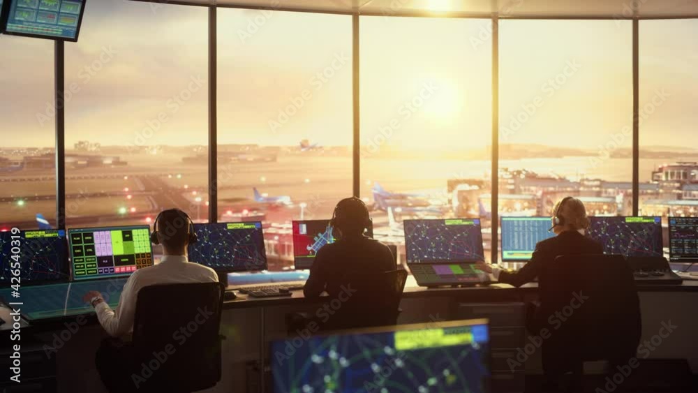 Diverse Air Traffic Control Team Working in Modern Airport Tower at Sunset. Office Room Full of Desktop Computer Displays with Navigation Screens, Airplane Departure and Arrival Data for Controllers. Diverse Air Traffic Control Team Working in Modern Airport Tower at Sunset. Office Room Full of Desktop Computer Displays with Navigation Screens, Airplane Departure and Arrival Data for Controllers.