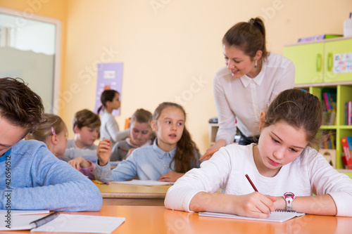 Young teacher woman and diligent schoolkids during lesson in classroom