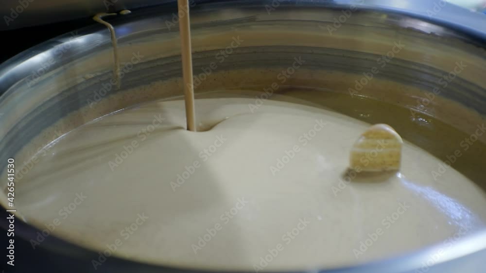 modern food production.technological process.melted liquid chocolate is mixed in a large industrial mixer.close-up.