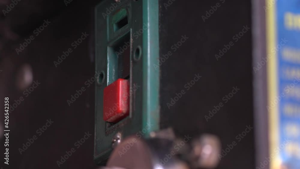 Close up of a builder, DIY enthusiast workman, or pressing the on and off button on a bench mounted press drill to drill a hole in  a piece of wood in the workshop.