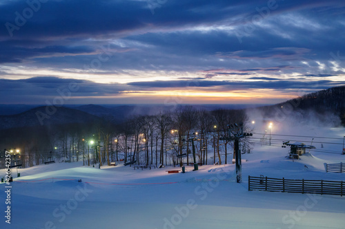 Winter sunrise at a ski resort, with mountains in background