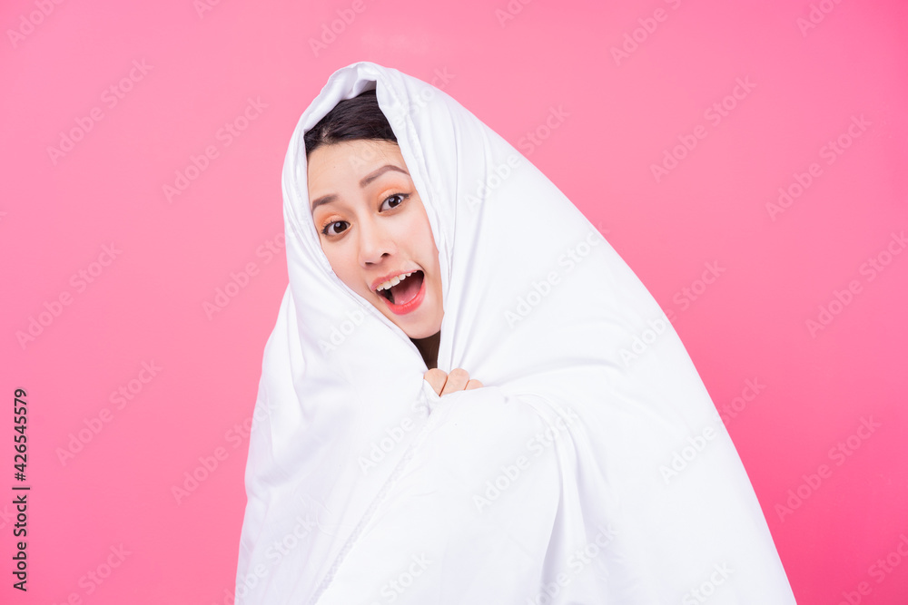 Asian woman curled up in blankets on pink background Asian woman curled up in blankets on pink background
