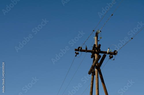 electric wooden pole with wires on a blue sky background
