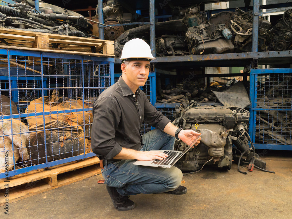 Engineer man working, Caucasian manager using laptop and looking at auto part in factory-warehouse Engineer man working, Caucasian manager using laptop and looking at auto part in factory-warehouse
