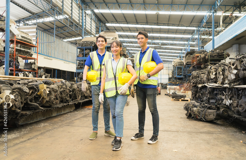 Woman and men work together, they hold helmets and look at same way. Asian engineer worker woman and man show teamwork by holding helmets and looking at same way in factory-warehouse