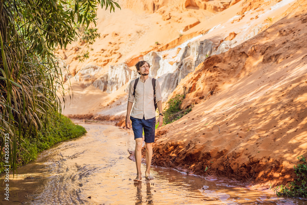 Man tourist on the Fairy stream among the red dunes, Muine, Vietnam. Vietnam opens borders after quarantine COVID 19 Man tourist on the Fairy stream among the red dunes, Muine, Vietnam. Vietnam opens borders after quarantine COVID 19