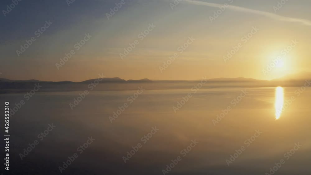 Vivid Sunrise Over Mist Covered Lake, Pan Left, Revealing Mountains and Trees Vivid Sunrise Over Mist Covered Lake, Pan Left, Revealing Mountains and Trees