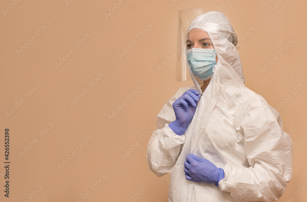 female doctor in a protective suit to combat the coronavirus pandemic covid-2019. Respirator, protective shield, gloves.