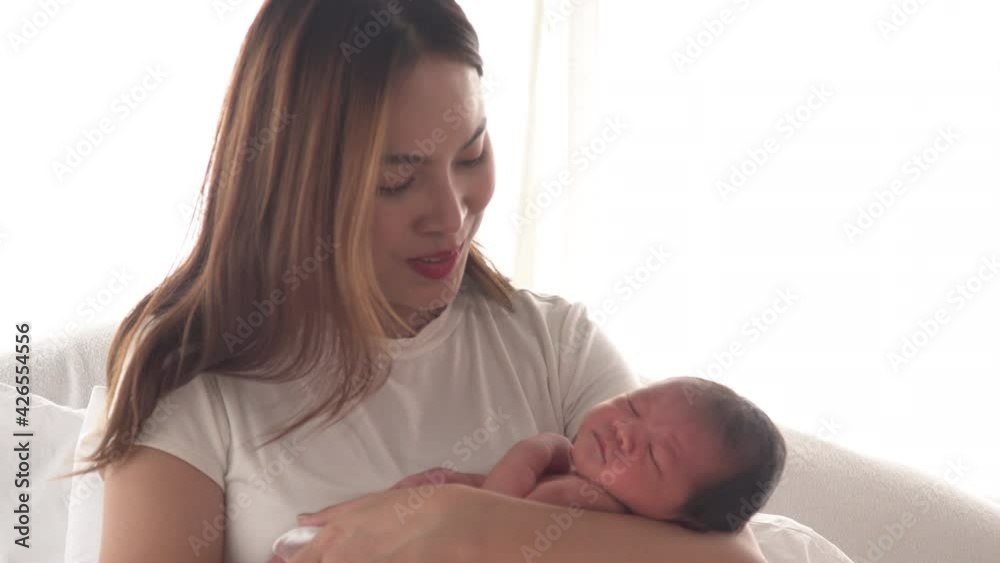 Pretty asian woman smile and holding a newborn baby in her arms. Happy family. Asia mother lifting and looking her adorable infant baby on white. love people concept Pretty asian woman smile and holding a newborn baby in her arms. Happy family. Asia mother lifting and looking her adorable infant baby on white. love people concept