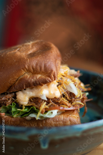 delicious burger with cheese and onions on a blue background and in a blue plate on a wooden table