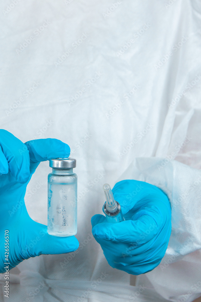 Fototapeta premium covid-19 sars-cov-2 vaccination: a health worker with a vaccine and a syringe in his hands