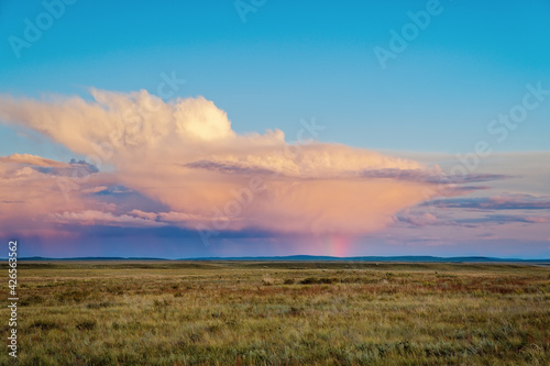 Thundercloud at sunset with streams of rain and a rainbow from the sun, Fields after rain, evening in Khakassia