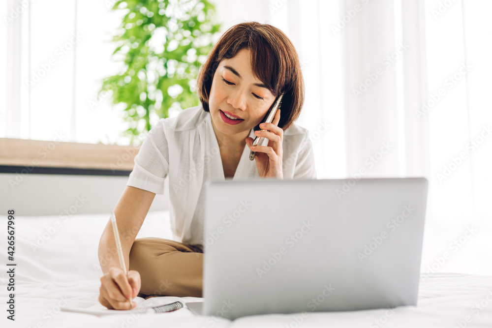 Young asian woman relaxing using laptop computer on bed in bedroom.woman checking social apps and working.Communication and technology concept Young asian woman relaxing using laptop computer on bed in bedroom.woman checking social apps and working.Communication and technology concept