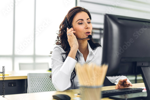 Beautiful happy call center smiling businesswoman operator customer support consult phone services agen working with wireless headset microphone and computer at call center office
