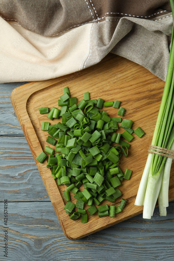Fresh green onion on cutting board, on gray wooden table Fresh green onion on cutting board, on gray wooden table