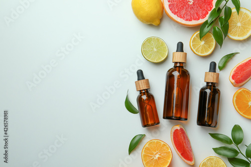 Dropper bottles with oil and different citrus on white background