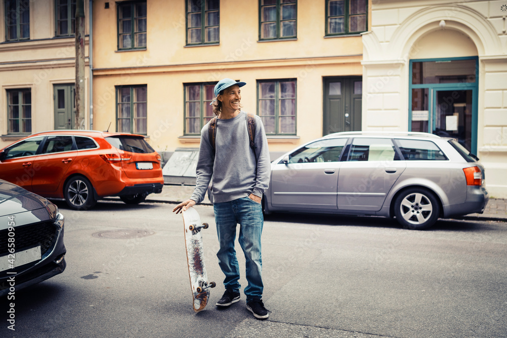 Male skateboarder with hand in pocket looking away while standing on street Male skateboarder with hand in pocket looking away while standing on street