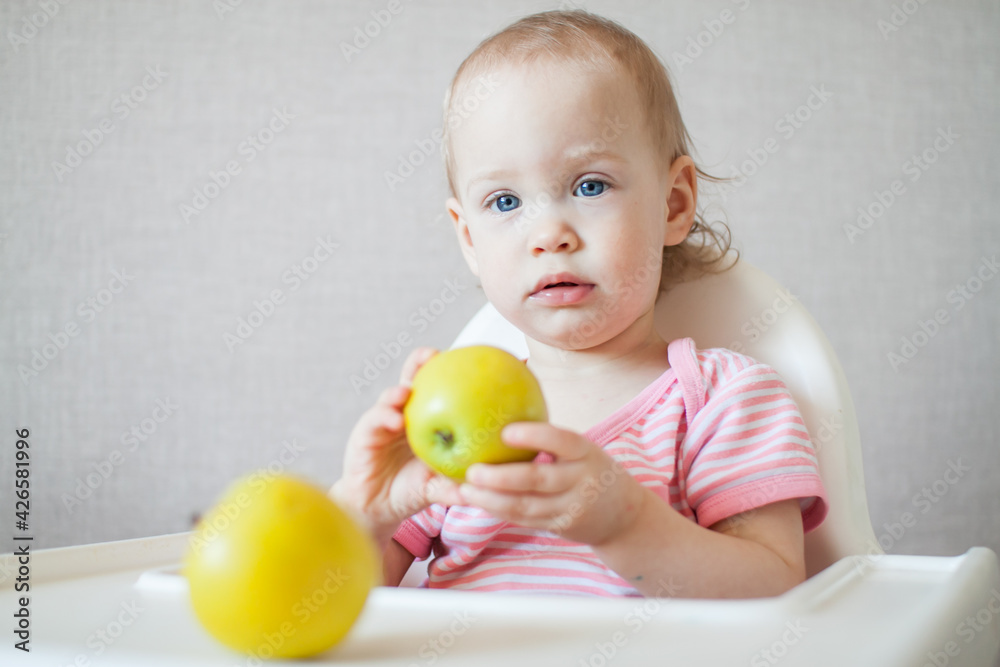 A little girl tastes, examines and plays with fresh apples with pleasure and interest. High quality photo A little girl tastes, examines and plays with fresh apples with pleasure and interest. High quality photo