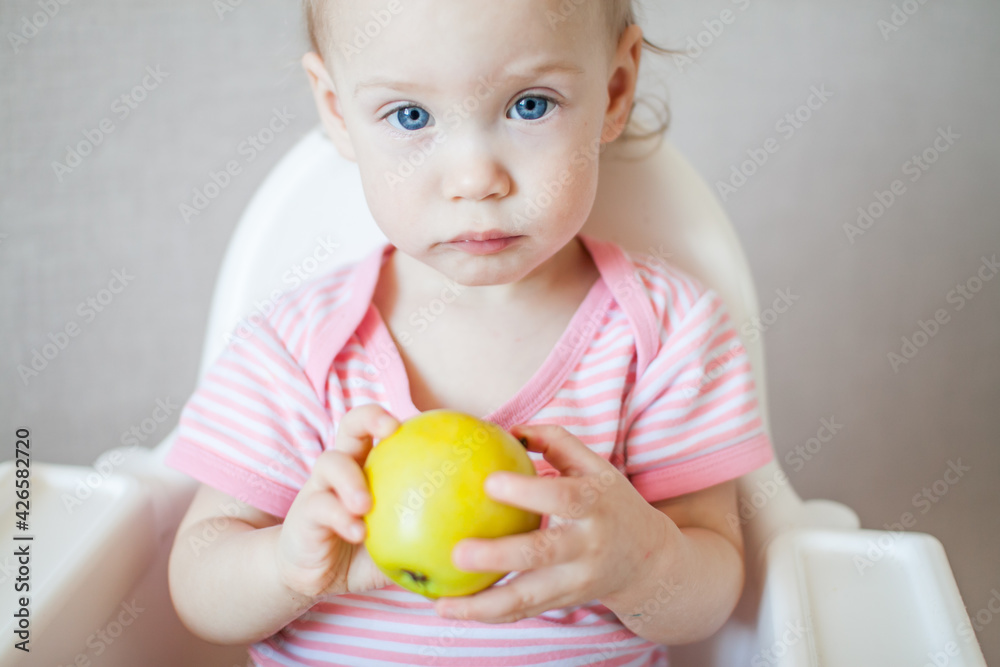 A little girl tastes, examines and plays with fresh apples with pleasure and interest. High quality photo A little girl tastes, examines and plays with fresh apples with pleasure and interest. High quality photo