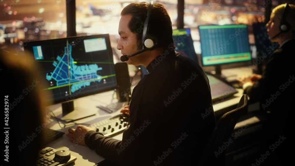 Portrait of Male Air Traffic Controller with Headset Talk on a Call in Airport Tower. Office Room is Full of Desktop Computer Displays with Navigation Screens, Airplane Flight Radar Data. Portrait of Male Air Traffic Controller with Headset Talk on a Call in Airport Tower. Office Room is Full of Desktop Computer Displays with Navigation Screens, Airplane Flight Radar Data.