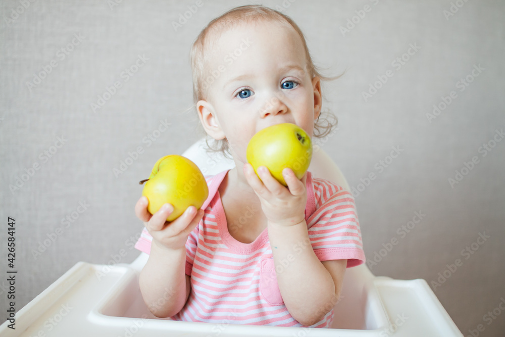 A little girl tastes, examines and plays with fresh apples with pleasure and interest. High quality photo A little girl tastes, examines and plays with fresh apples with pleasure and interest. High quality photo