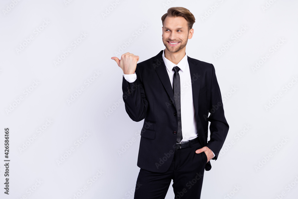 Photo of young man happy positive smile indicate thumb empty space ad promo choice isolated over grey color background Photo of young man happy positive smile indicate thumb empty space ad promo choice isolated over grey color background