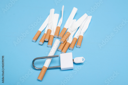 Quit smoking concept. Cigarettes squeezed into a lock on a blue background. Bad limiting habit.