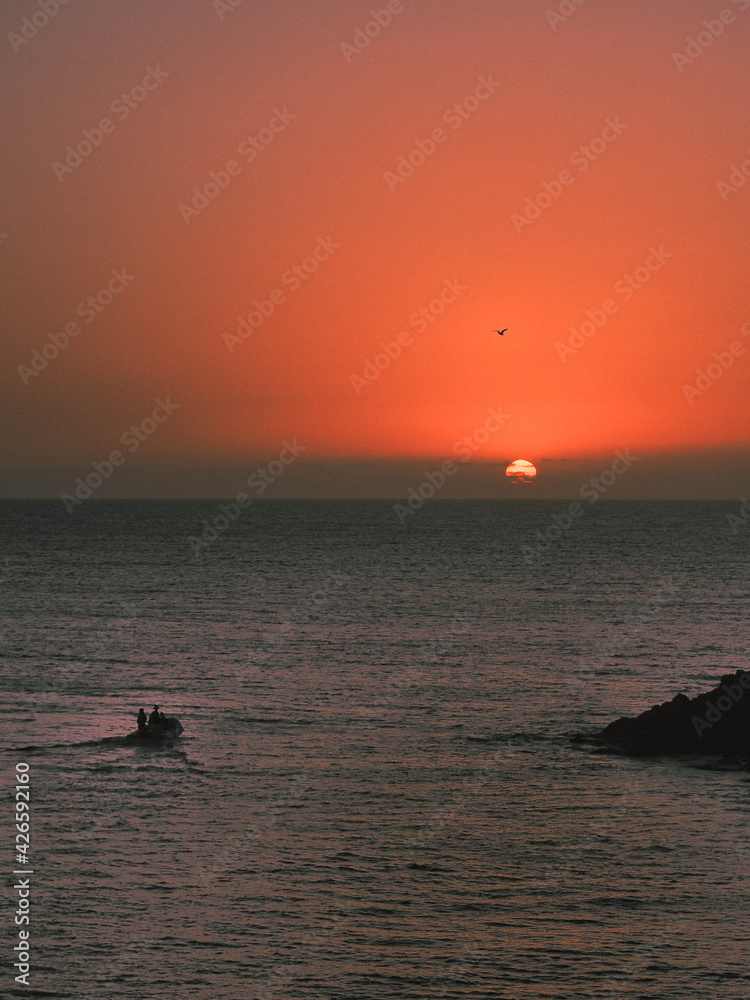 Fototapeta premium Atardecer desde la playa con barca yendo al horizonte