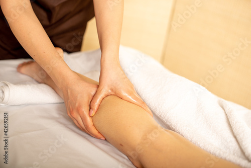 Foot and calf massage by a physiotherapist. Young girl is relaxing in the spa. Foot massage. Anticellulite massage
