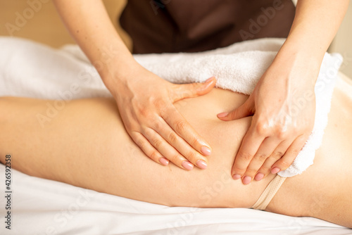 Closeup photo of the anticellulite massage by a physiotherapist. Young girl is relaxing in the spa. Foot massage. photo