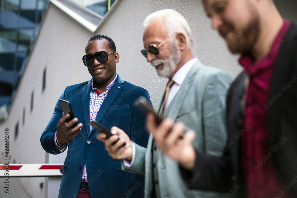 © liderina - Three business men in the city standing on street and using mobile phones © liderina - Three business men in the city standing on street and using mobile phones