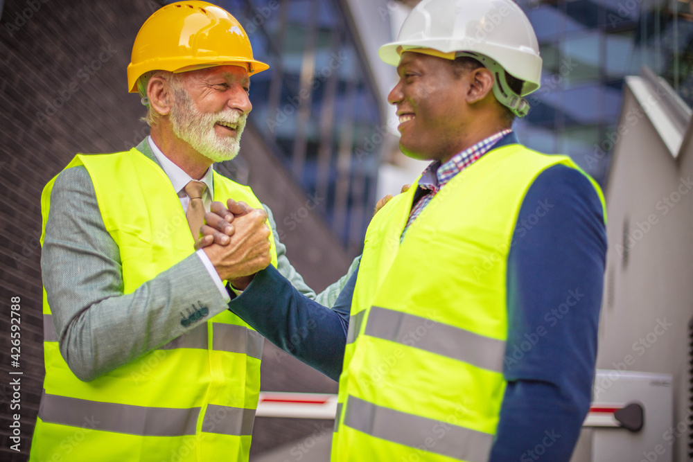 Mature engineer discussing the structure of the building with architects colleague at construction site. Mature engineer discussing the structure of the building with architects colleague at construction site.