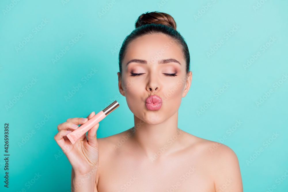 Portrait of attractive flirty trendy girl holding in hand tube balm sending air kiss isolated over bright teal turquoise color background Portrait of attractive flirty trendy girl holding in hand tube balm sending air kiss isolated over bright teal turquoise color background