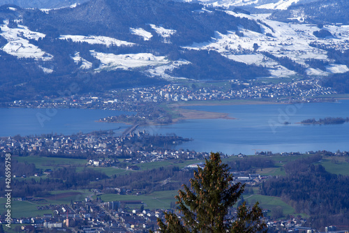Panoramic landscape with lake Zurich and snow capped Swiss alps in the background. Photo taken April 8th, 2021, Zurich, Switzerland.